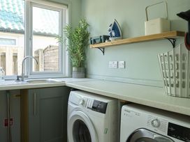 A laundry room with washing machine and shelf at Harbour Lights Southwold