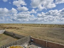 An outdoor area with a grill and a view of grass and sand dunes at Harbour Lights in Southwold