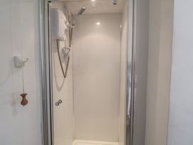 A shower with a glass door and water heater at High Ground, Reydon