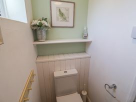 A bathroom with a toilet and shelf at High Ground, Reydon