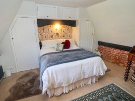 A bedroom with a bed and a bookshelf at Cherry Tree Cottage, Woodbridge