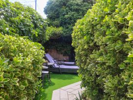 A garden with hedges and a lounge chair at Cherry Tree Cottage, Woodbridge