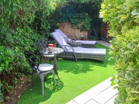 A garden with lounge chairs and a table at Cherry Tree Cottage, Woodbridge