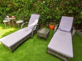 A garden with lounge chairs and a table at Cherry Tree Cottage, Woodbridge