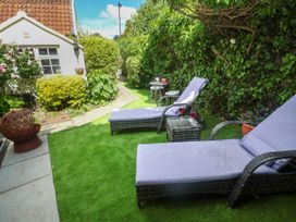 A garden with chaise lounges and a table at Cherry Tree Cottage, Woodbridge