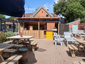 An outdoor seating area with tables and chairs near a bar at Cherry Tree Cottage, Woodbridge
