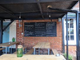 An outdoor dining area with a menu board and wooden tables at Cherry Tree Cottage, Woodbridge