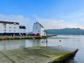 A view of waterfront buildings with a dock and boats at Cherry Tree Cottage, Woodbridge
