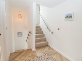 A stairway with a wall light and painting at Salt Marsh House, Southwold