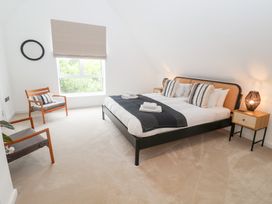 A bedroom with a bed, chair, and bedside table at Salt Marsh House, Southwold