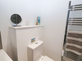 A bathroom featuring a toilet, mirror, shelf with toiletries and a towel rack at Salt Marsh House, Southwold