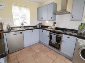 A kitchen with a dishwasher, sink, kettle, oven, and washing machine at 1 Coconut Cottage, Long Melford