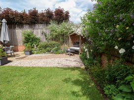 A garden with a bench, table, and flowers at 1 Coconut Cottage, Long Melford