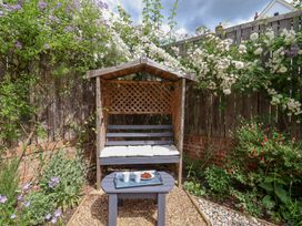 A garden with a bench, table, and flowers at 1 Coconut Cottage, Long Melford