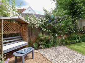 A garden with a bench and coffee table at 1 Coconut Cottage, Long Melford