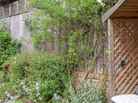 A garden with flowering plants and a wooden fence at 1 Coconut Cottage, Long Melford