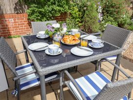 A table set with food and drinks in an outdoor dining area at 1 Coconut Cottage, Long Melford
