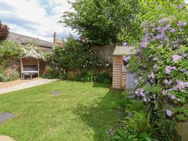 A garden with a bench and flowering plants at 1 Coconut Cottage, Long Melford