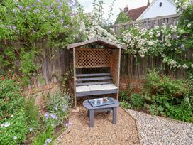 A bench with a table and cups in a garden at 1 Coconut Cottage, Long Melford