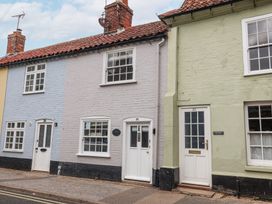 Three adjoining brick houses painted blue gray and green with white doors and windows at Dolphin Cottage Southwold