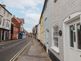 A street with brick buildings painted in various colors and closed shops in Southwold
