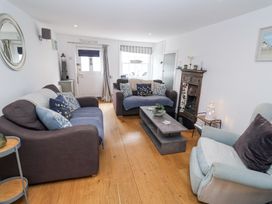 A living room with two brown sofas a light blue armchair a wooden floor and a coffee table at Dolphin Cottage Southwold