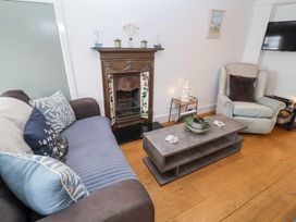 A living room with a sofa, armchair, coffee table, fireplace and wall-mounted TV at Dolphin Cottage Southwold