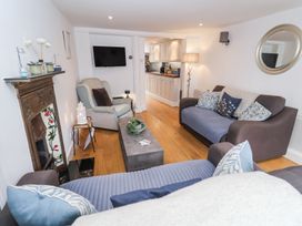 A living room with two sofas a armchair a coffee table and a wall-mounted television at Dolphin Cottage in Southwold