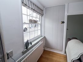 A corner with a window and a door next to a radiator and a sofa with a blanket at Dolphin Cottage Southwold