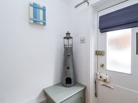 A corner of a room with a white door featuring a blue blind and a decorative lighthouse on a green cabinet at Dolphin Cottage Southwold