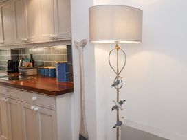 A kitchen corner with white cabinets wooden countertop and a lamp with decorative birds at Dolphin Cottage Southwold