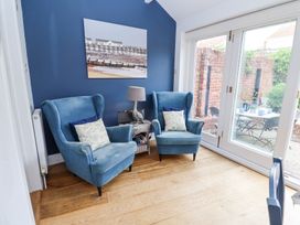 A sitting area with two blue armchairs a side table with a lamp and a painting on a blue wall at Dolphin Cottage Southwold
