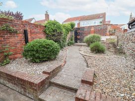 A garden area with a brick and stone pathway surrounded by gravel beds and bushes at Dolphin Cottage Southwold
