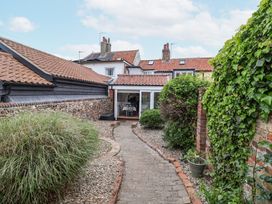 A garden pathway with bushes on either side leading to a house with tiled roofs at Dolphin Cottage Southwold