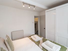 A bedroom with a bed with folded towels and pillows beside a white sliding door wardrobe at Dolphin Cottage Southwold