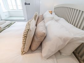 A bedroom with a bed made with pillows and folded towels next to a window at Dolphin Cottage Southwold