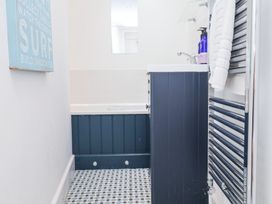 A bathroom with a bathtub a sink cabinet a mirror a towel rack with towels and a wall decoration at Dolphin Cottage Southwold