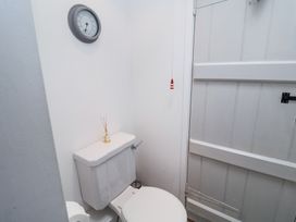 A small bathroom with a white toilet a clock on the wall and a white wooden door at Dolphin Cottage Southwold