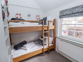 A bedroom with wooden bunk beds near a window and nautical decor at Dolphin Cottage Southwold