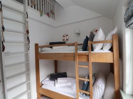 A small bedroom with wooden bunk beds pillows towels and a white ladder at Dolphin Cottage Southwold