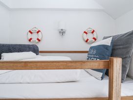 A bed with pillows and towels under wall lights and lifesaver decorations at Dolphin Cottage Southwold