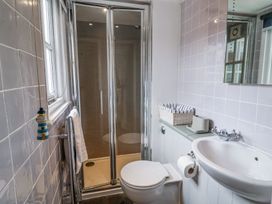 A bathroom with a shower with glass doors a toilet a sink and a towel rail at Dolphin Cottage Southwold