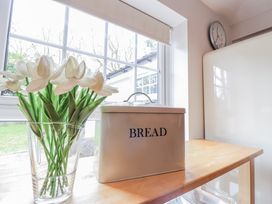 A kitchen with a bread box and flowers on a table at Fig Cottage, Pettistree near Woodbridge