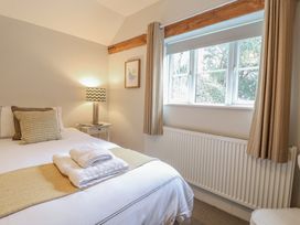 A bedroom with a bed, lamp, and window at Fig Cottage, Pettistree Near Woodbridge