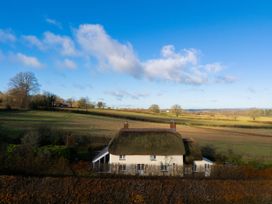 A cottage with a thatched roof in a field at Rose Cottage Okehampton