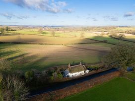 A cottage near a road with fields and trees at Rose Cottage Okehampton