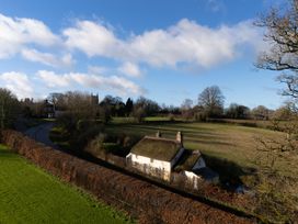A thatched cottage near a road and fields at Rose Cottage in Okehampton