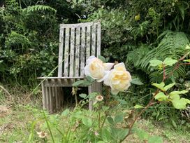 A garden with a wooden bench and rose flowers at Rose Cottage in Okehampton
