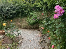 A garden with a gravel path and various flowers at Rose Cottage in Okehampton
