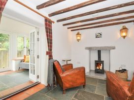 A living room with an armchair and a wood stove at Rose Cottage Okehampton